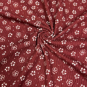 May include: Red ribbed fabric with a white floral pattern. The fabric is textured and has a subtle sheen.