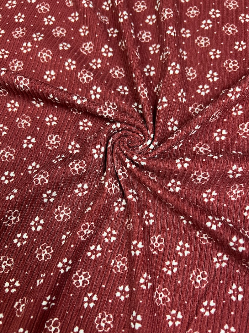 May include: Red ribbed fabric with a white floral pattern. The fabric is textured and has a subtle sheen.