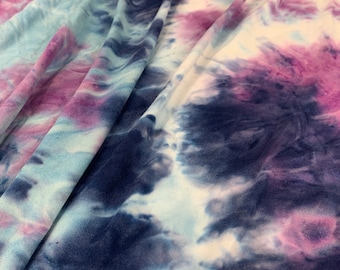 May include: A close-up of a tie-dye fabric with shades of blue, purple, and white. The fabric has a soft, flowing texture and a unique, abstract pattern.