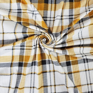 May include: White fabric with a yellow and black plaid pattern. The fabric has a ribbed texture.
