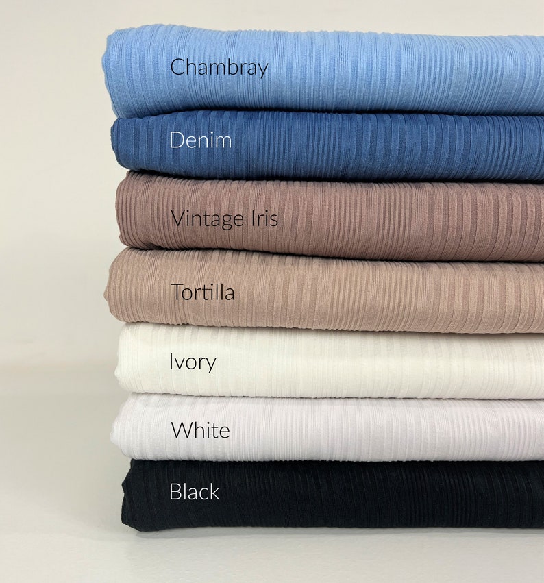 May include: A stack of seven fabric swatches in various colours, including black, white, ivory, tortilla, vintage iris, denim, and Chambray.