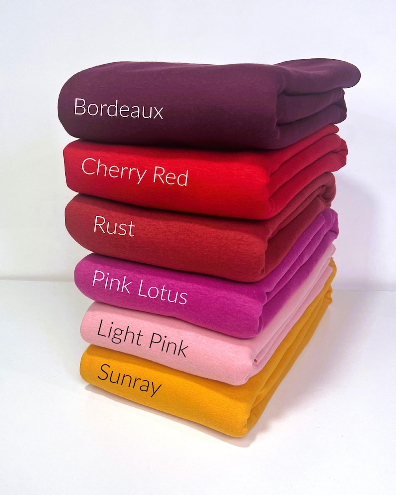 May include: A stack of six fabric swatches in different shades of red, pink, and yellow. The swatches are labeled "Bordeaux", "Cherry Red", "Rust", "Pink Lotus", "Light Pink", and "Sunray".