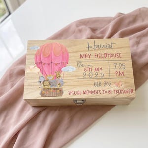 May include: A rectangular wooden keepsake box featuring a printed illustration of a pink hot air balloon carrying cartoon animals. The text reads Harriet, May Fieldhouse, Born on 6th July 2025, 7:25 P.M., 6lb 2oz, and Special Memories To Be Treasured.