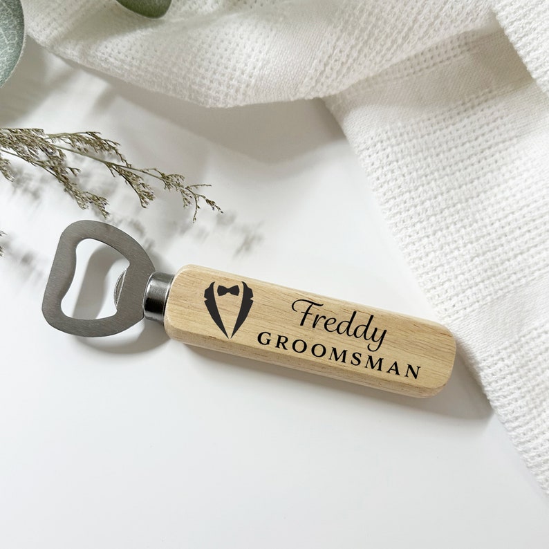 May include: Wooden bottle opener with a tuxedo design and the text "Freddy GROOMSMAN" engraved on it.