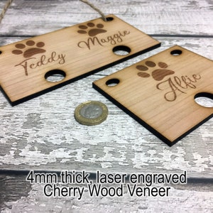 Pu&ograve; includere: Due targhette per nomi di animali domestici in legno con impronte di zampe e i nomi "Teddy" e "Maggie" su un'etichetta e "Alfie" sull'altra. Le targhette sono spesse 4 mm e realizzate in legno di ciliegio.