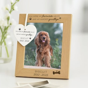 May include: A light oak picture frame with a photo of a Cocker Spaniel. The frame is inscribed with the words "YOU WERE MY favourite HELLO AND MY HARDEST goodbye..." and "BISCUIT 2012-2025". A heart-shaped tag with the same text hangs from the frame.
