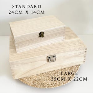 Może przedstawiać: Dwa drewniane pudełka z pokrywkami i zatrzaskami. Mniejsze pudełko jest oznaczone "STANDARD 24CM X 14CM", a większe pudełko jest oznaczone "LARGE 35CM X 22CM".