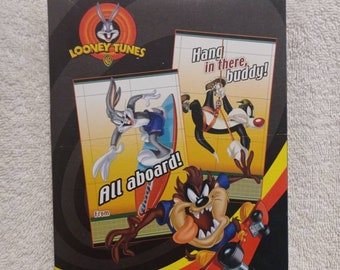 May include: A package of 32 Looney Tunes Valentines featuring Bugs Bunny, Tweety Bird, and Taz. The package has a black background with a red and yellow border. The text on the package reads "32 Valentines includes 32 Fold & Seal Cards With Seals" and "www.looneytunes.com".