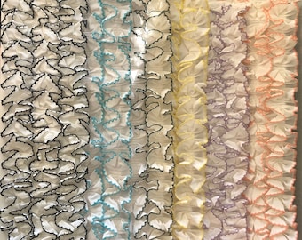 Puede incluir: Cinco tiras de tela blanca con bordes ondulados de diferentes colores. Los bordes son negros, azul claro, amarillo, lavanda y melocotón.