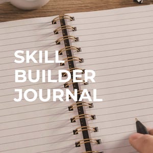 Può includere: Quaderno aperto con pagine a righe e la scritta "SKILL BUILDER JOURNAL" in bianco. La rilegatura a spirale è nera con anelli metallici color oro. Una mano tiene una penna, pronta a scrivere. Una tazza bianca sullo sfondo.