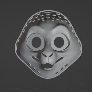 May include: A gray, stylized mask with large eye openings and a small nose and mouth. The mask has a series of small holes around the edges and top. The overall shape is rounded, resembling a cartoon character.