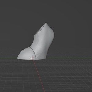 May include: A 3D-rendered, gray high-heeled shoe model. The shoe is segmented into two parts, with a curved heel and a pointed toe. The model is set against a dark gray background with a grid.