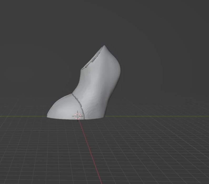May include: A 3D-rendered, gray high-heeled shoe model. The shoe is segmented into two parts, with a curved heel and a pointed toe. The model is set against a dark gray background with a grid.