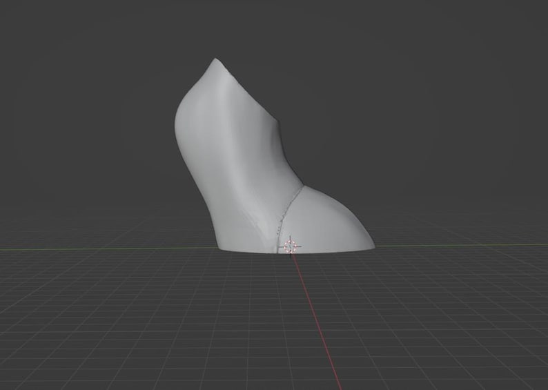 May include: A light gray, curved object, possibly a shoe heel, is depicted against a dark gray background. The object has a smooth surface and a rounded shape, with a seam visible near the base. The image is set against a grid.