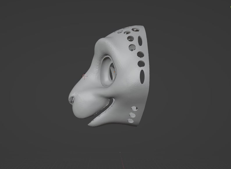 May include: A light gray, 3D-rendered mask in the shape of a stylized animal head, possibly a feline or canine. The mask has large eye sockets, a snout, and a smiling mouth. The side of the mask features several circular and oval cutouts.
