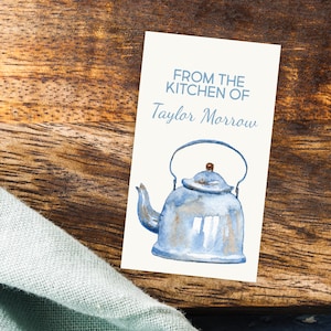 May include: A white card with the text "From the kitchen of Taylor Morrow" and a watercolor illustration of a blue teapot.