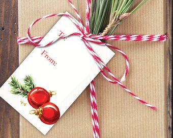 May include: A white gift tag with red text that says "To:" and "From:". The tag has a watercolor illustration of two red Christmas ornaments with gold accents and a green pine branch.