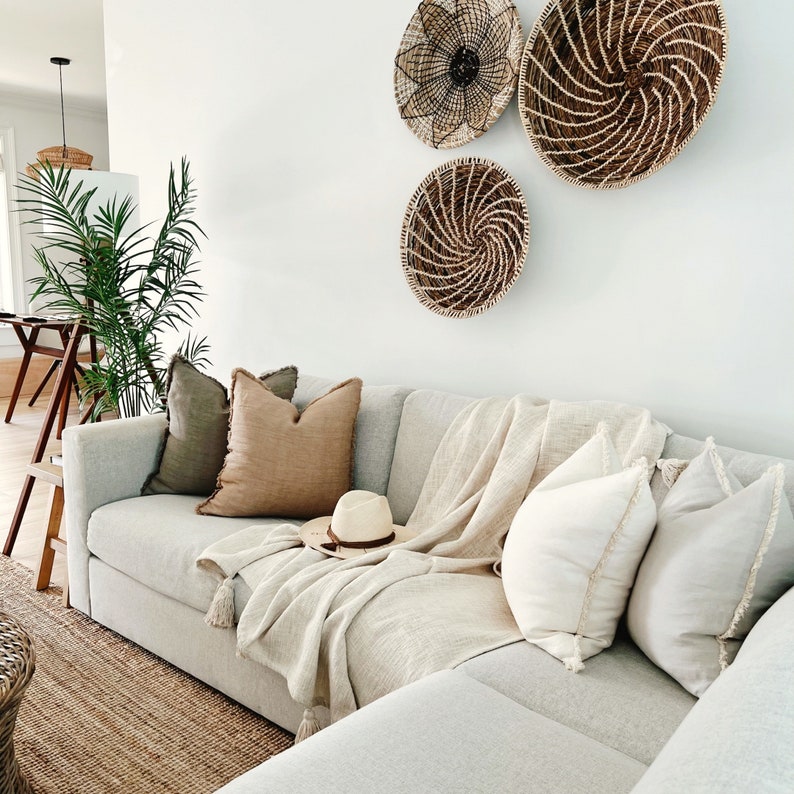 May include: A white sectional sofa with a throw blanket and pillows. The sofa is in a living room with three woven wall baskets.