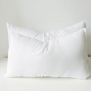 May include: Two white pillowcases stacked on top of each other. The pillowcases are made of a soft, smooth fabric.