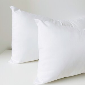 May include: Two white pillowcases, one on top of the other, with a smooth, wrinkle-free surface.