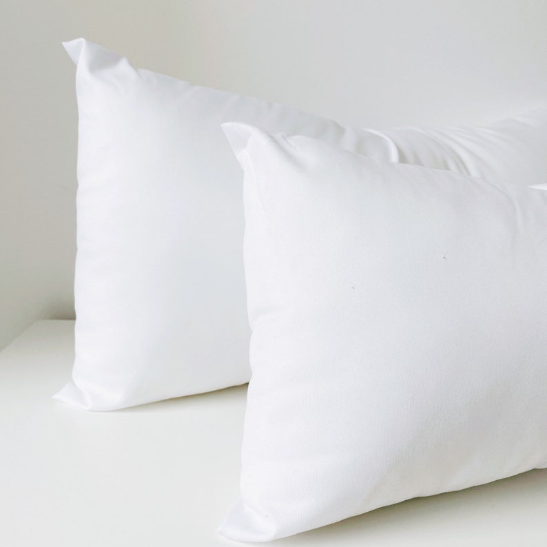May include: Two white pillowcases, one on top of the other, with a smooth, wrinkle-free surface.