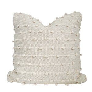 May include: A cream coloured throw pillow with a textured woven design featuring small raised bumps.