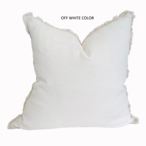 May include: Off-white throw pillow with a fringed edge.
