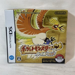 May include: A Nintendo DS game box for Pokémon HeartGold featuring the legendary Pokémon Ho-Oh on a gold background. The box displays the Nintendo DS logo, The Pokémon Company branding, the Japanese title, a CERO A rating, and a Pokéwalker icon.