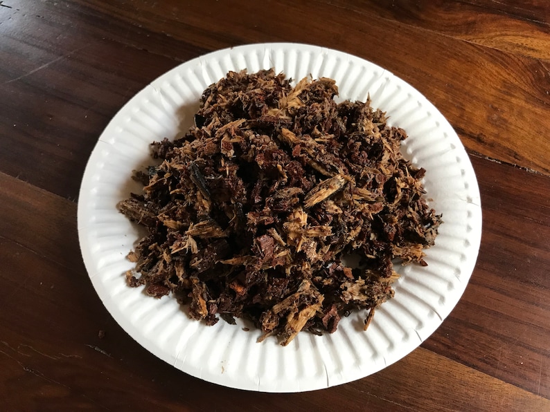 May include: A white paper plate filled with brown wood chips.