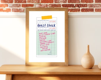 May include: A framed print of a guest check with a green background and blue and pink text. The text reads "Guest Check" and lists various food items, including chef salad, apple pie, ice cream, and vanilla strawberry. The check number is 071289.