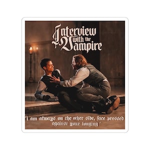May include: A sticker featuring a scene from "Interview with the Vampire." The image shows two people in a dramatic pose, with the title text at the top. The quote "I am always on the other side, face pressed against your longing" is at the bottom.