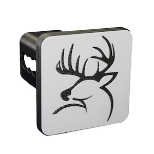 May include: A black and silver hitch cover with a deer silhouette design. The deer has large antlers and is facing to the right.