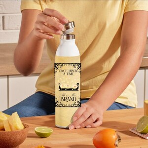 Könnte beinhalten: Eine weiße Wasserflasche mit einem schwarzen und goldenen Design. Das Design zeigt den Text "Once Upon A Time" und "Mr. & Mrs. Brand".