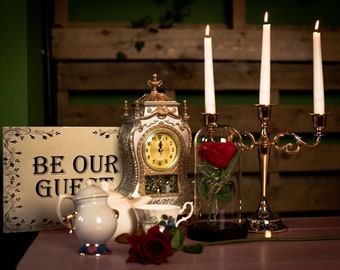 Centro de mesa con reloj de La Bella y la Bestia, candelabro dorado, tetera, taza de té, cúpula de rosas, azucarero, pétalos de rosa, una rosa, letrero de boda de cuento de hadas