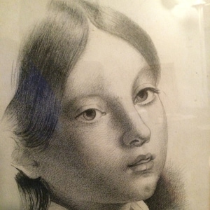 May include: A black and white pencil drawing of a young person with long hair, looking to the right. The drawing is signed "P. Melby. 22."