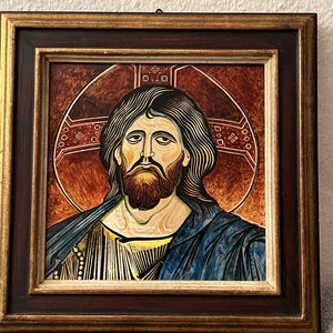 May include: A framed stained glass icon depicting Jesus Christ with a red and gold background. The icon is in a dark wood frame with a gold trim.