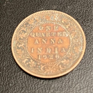 May include: A copper coin from British India with the inscription "ONE QUARTER ANNA INDIA 1920" surrounded by a decorative floral design.