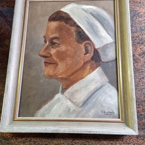 Op de afbeelding: Een ingelijst olieverfschilderij van een vrouw met een witte muts en een wit shirt. Het schilderij is rechtsonder gesigneerd met "E. Hortwis 66".