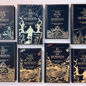 May include: A collection of ten black hardcover books with gold lettering and illustrations. The books are titled "The Book of Mormon" and "El Libro de Mormón".
