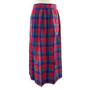 May include: A floor-length skirt featuring a vibrant plaid pattern in shades of red, blue, and green. The garment has a high-waisted design with vertical pleats extending from the waistband, creating a full, flowing silhouette that reaches the ankles.
