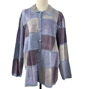 May include: A long-sleeve button-down jacket constructed from a patchwork of suede leather squares in various shades of purple, lavender, and gray. The garment features a pointed collar and visible decorative stitching along the seams.