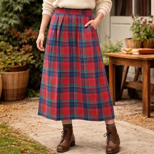 May include: A midi-length tartan skirt in red, green, and blue. The skirt features pleats and pockets. The person is wearing brown boots and a cream-coloured jumper. The skirt is a classic design.
