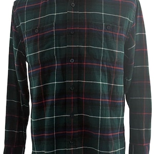 May include: A long-sleeved, button-down flannel shirt in a green, navy, red, and white plaid pattern. The shirt has two chest pockets and a classic collar. The fabric appears soft and comfortable.
