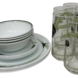 May include: A white dinner service with black and green floral patterns. The set includes bowls, plates, and an oval platter. Six tall drinking glasses with matching floral designs are also present, creating a cohesive dining aesthetic.