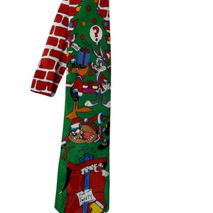 May include: A novelty necktie featuring a Christmas tree design with Looney Tunes characters. The tie has a red brick pattern on the back and a green front with Bugs Bunny, Daffy Duck, and Taz. The tie has the text "For Tweety".
