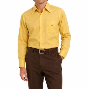May include: A yellow long-sleeve shirt with a chest pocket and the text "RAB". The shirt is paired with brown trousers and a brown belt. The outfit is suitable for business or casual wear.