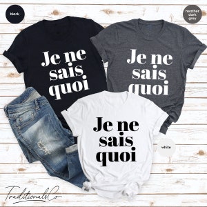 May include: Three t-shirts with the French phrase "Je ne sais quoi" printed in black on them. The shirts are in black, heather dark grey, and white.