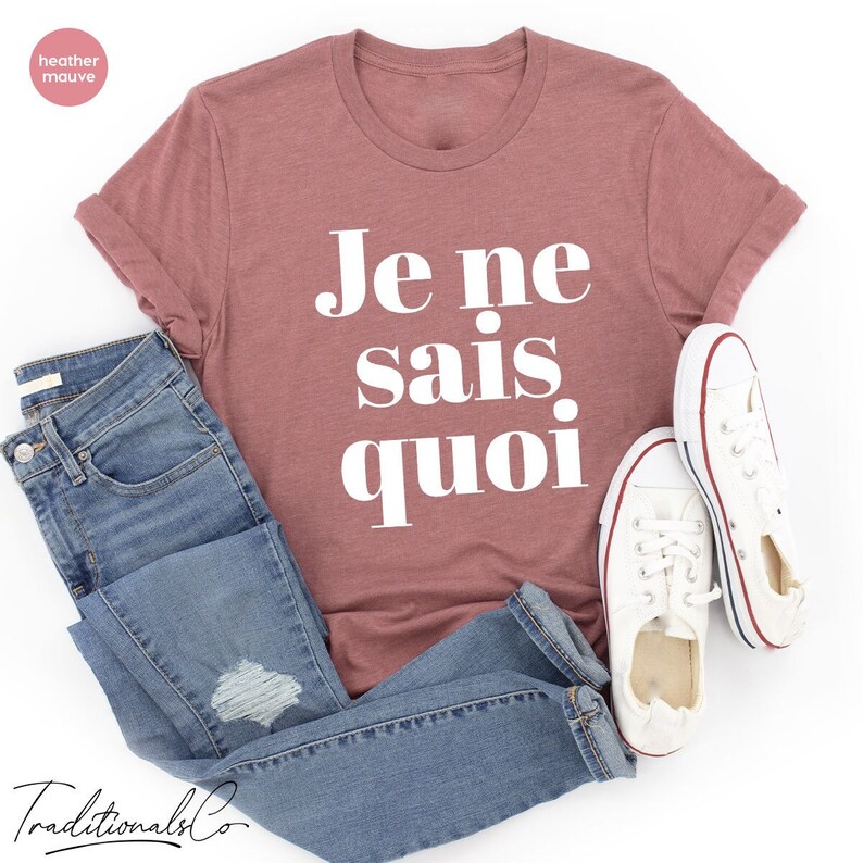 May include: A heather mauve t-shirt with the French phrase "Je ne sais quoi" printed in white on the front.