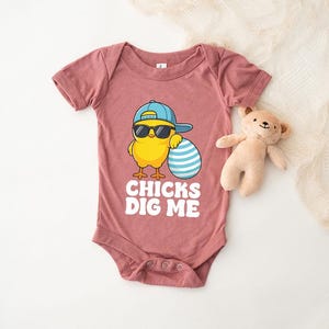 a baby onesuit with a teddy bear next to it