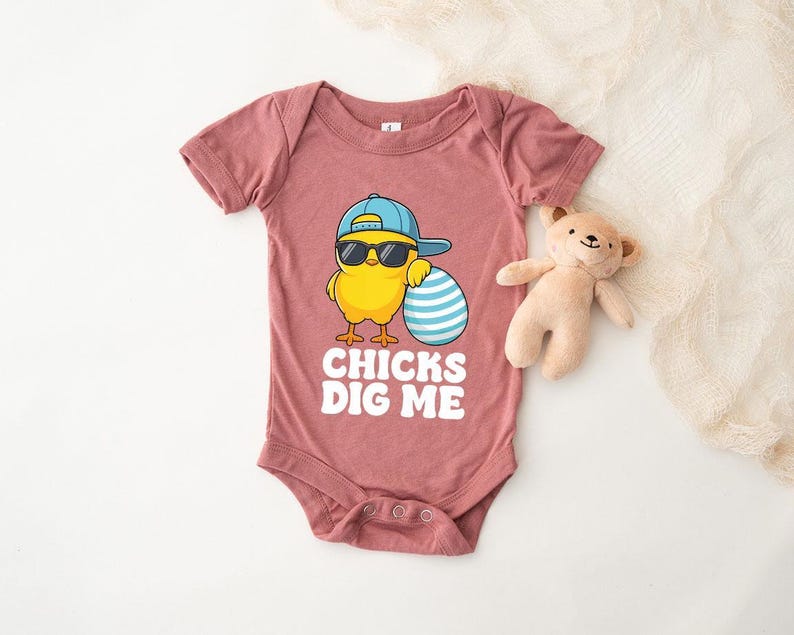 a baby onesuit with a teddy bear next to it